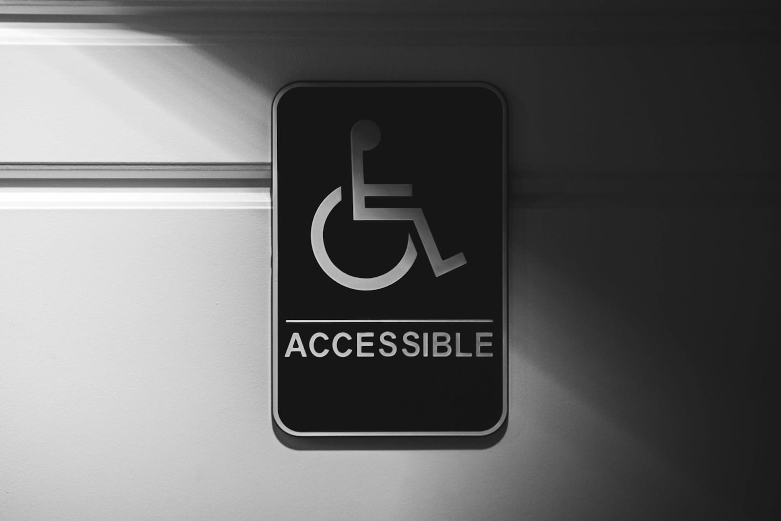 Black and white accessible signage hanging on a white door with half dim lighting.