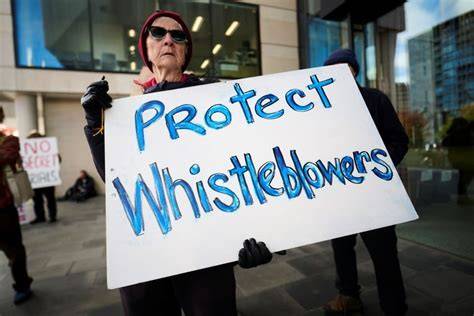 The image features a protester holding a sign advocating for the protection of individuals who expose wrongdoing.
Protect Whistleblowers
The message demands legal protection for those reporting unethical or illegal activities.